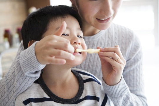 A mom helping her son brush his teeth